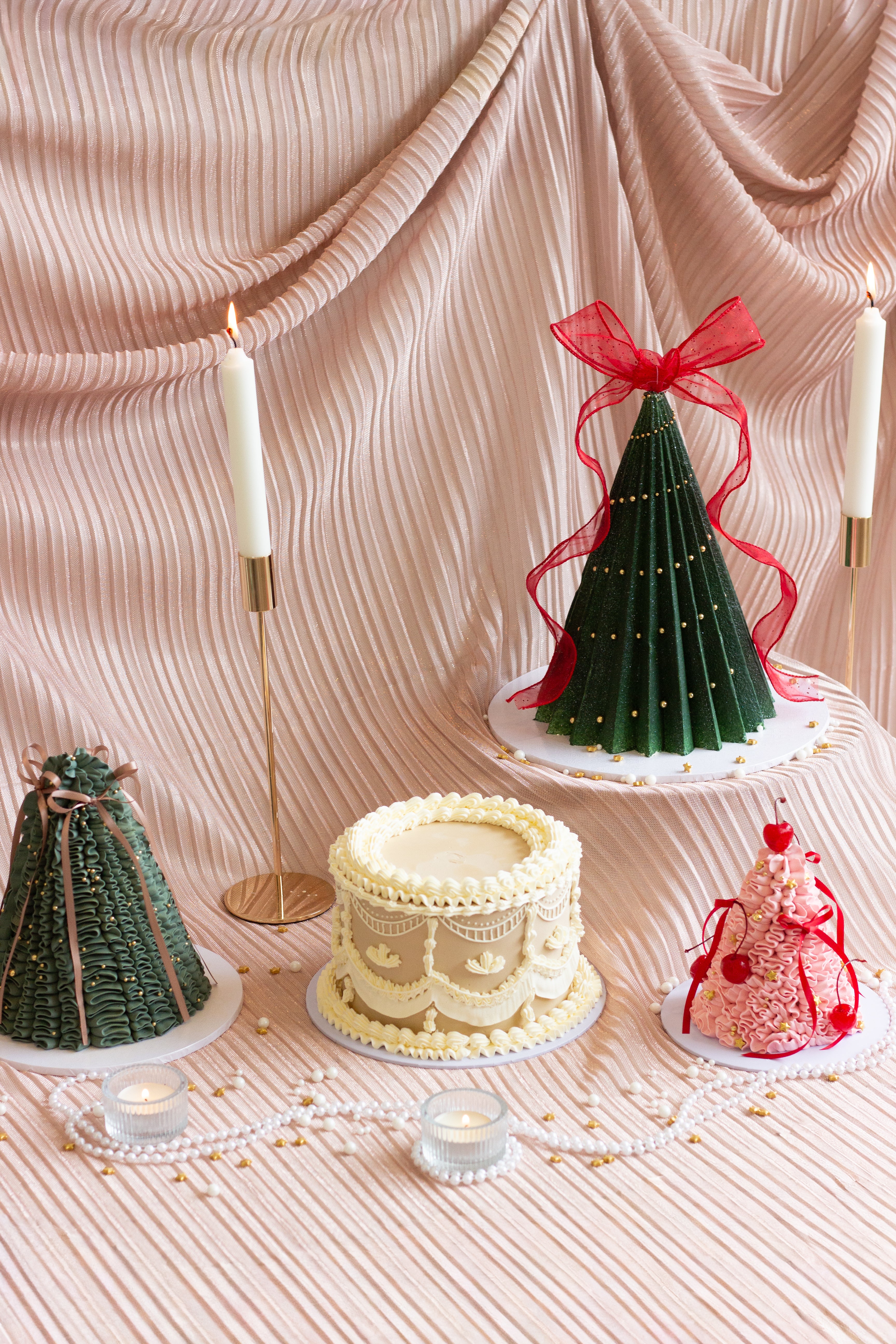 Pink Christmas tree shaped cake with expressive buttercream piping, red ribbons, and cherries on top.