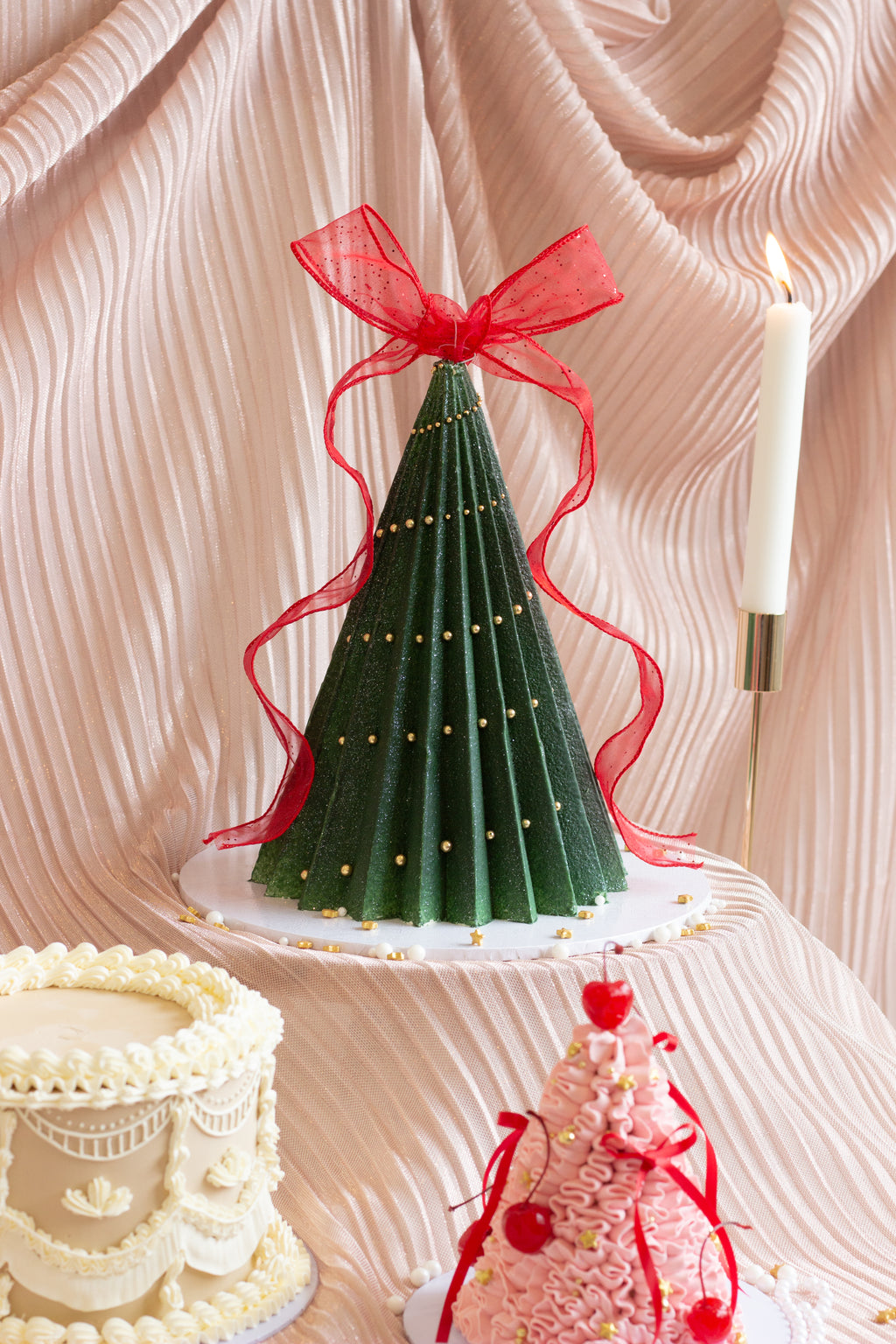 A handcrafted Christmas tree cake featuring deep green buttercream ruffles, delicate ribbon details, and a festive sculpted design. Perfect for holiday tables and gift giving in Melbourne and beyond. Cake Melbourne. Christmas cake Melbourne.
