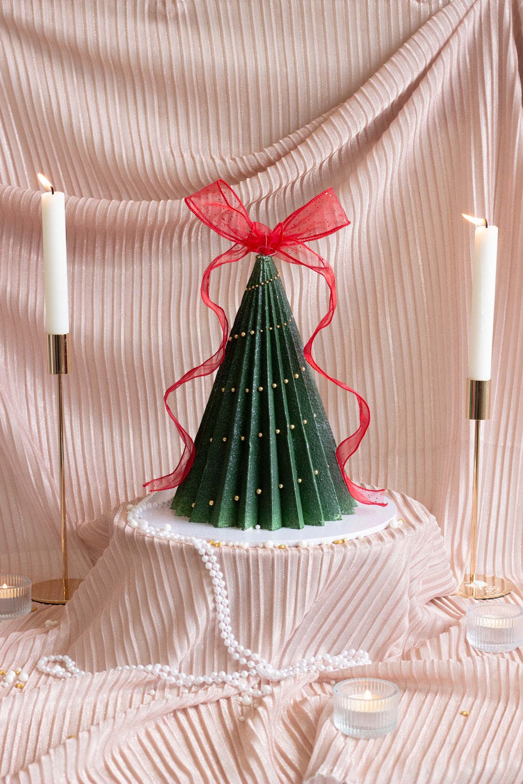 A handcrafted Christmas tree cake featuring deep green buttercream ruffles, delicate ribbon details, and a festive sculpted design. Perfect for holiday tables and gift giving in Melbourne and beyond. Cake Melbourne. Christmas cake Melbourne.
