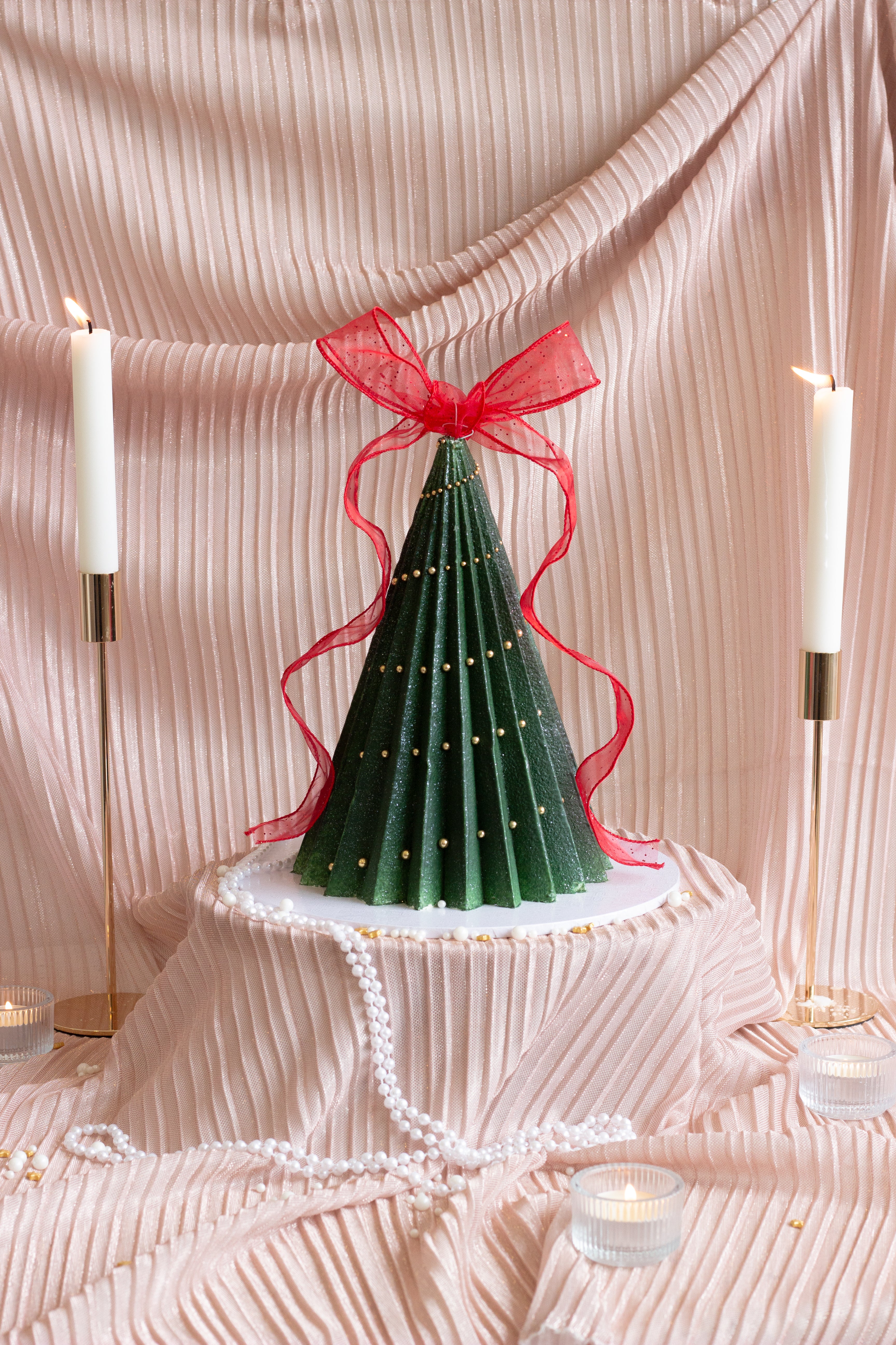 A handcrafted Christmas tree cake featuring deep green buttercream ruffles, delicate ribbon details, and a festive sculpted design. Perfect for holiday tables and gift giving in Melbourne and beyond. Cake Melbourne. Christmas cake Melbourne.