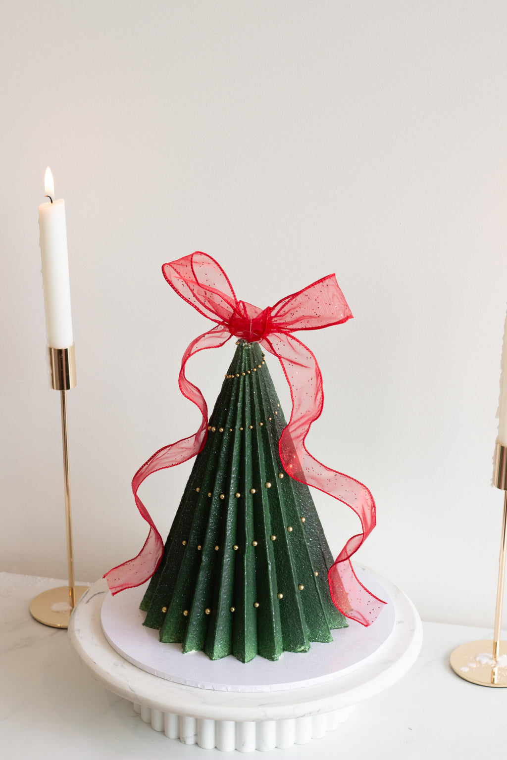 A handcrafted Christmas tree cake featuring deep green buttercream ruffles, delicate ribbon details, and a festive sculpted design. Perfect for holiday tables and gift giving in Melbourne and beyond. Cake Melbourne. Christmas cake Melbourne.